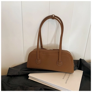 Detail of brown tote bag with white contrast stitching and dual zipper closures