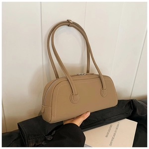 Detail of light brown tote bag featuring contrast stitching and silver zipper closure