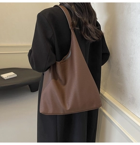 Detailed view of large brown lychee pattern leather tote bag on model shoulder