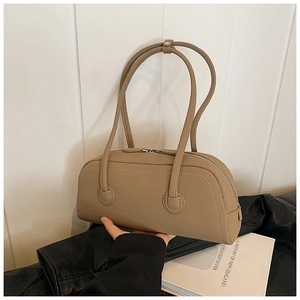 Detail view of khaki leather tote with white contrast stitching and dual zipper closure