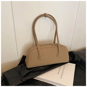 Detail of khaki leather bowling bag with dual zippers and long handles on a leather backdrop