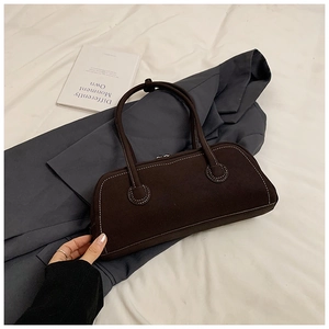 Detail of dark brown tote bag with white contrast stitching on minimalist fabric