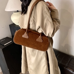 Brown suede bowling bag with leather straps worn by model in a beige trench coat