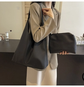 Detailed view of black pebbled leather tote bag with a matching zippered clutch set