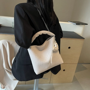 Sac seau tissé blanc crème avec poignée tressée et pendentif coeur dans un cadre minimaliste