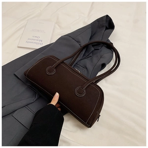 Detail of deep brown tote bag featuring white contrast stitching and zip closure