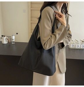 Lifestyle shot of large black pebbled leather tote bag worn by a model in a cafe