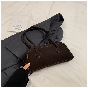 Close-up of retro dark brown suede tote bag with contrast stitching on grey blazer