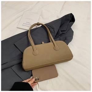 Detailed view of khaki leather tote bag stitching on a blazer with lifestyle accessories
