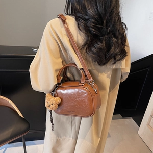 Vintage brown glossy boston bag with teddy charm on beige trench coat model