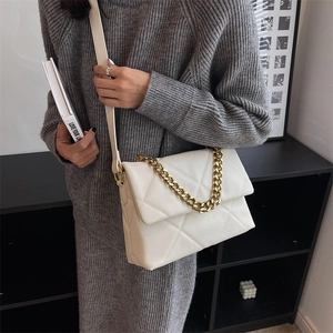 Chic white quilted crossbody bag with gold chain strap worn with a grey knit dress