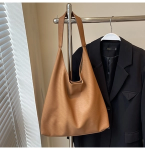 Detail of large brown tote bag with lychee texture hanging next to a black blazer