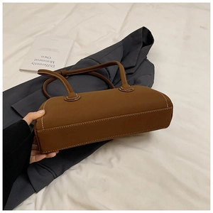 Detail of dark brown tote bag with white contrast stitching and round top handles