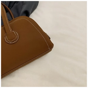 Detail shot of brown vintage leather tote with white contrast stitching and rounded handle
