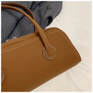 Detail of brown leather tote bag featuring white contrast stitching and matte finish