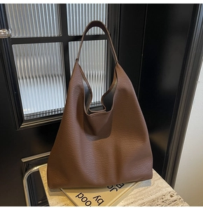 Detail of deep coffee tote bag with lychee grain texture and grey suede lining