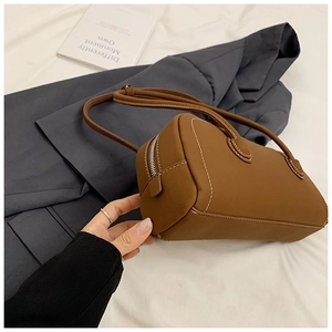 Detail of caramel leather tote bag with white contrast stitching and zip closure