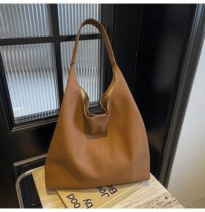 Detailed macro shot of the brown pebbled leather texture on a large hobo shoulder bag