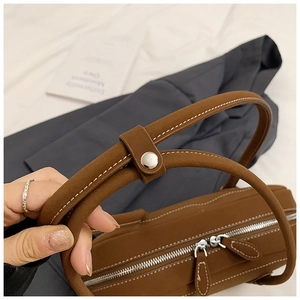 Detail of brown leather tote with white contrast stitching and dual zipper closure