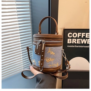 Détail de la broderie florale sur sac seau en denim bleu avec garniture en cuir synthétique