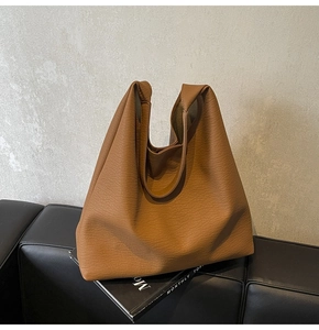 Detail of soft brown lychee grain leather tote bag showing high-quality texture and draping