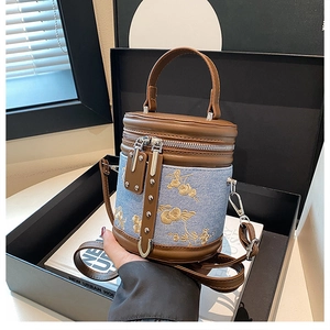 Vue détaillée du sac seau en denim avec broderie florale dorée et finitions en cuir brun
