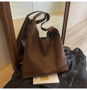 Detailed macro view of the premium litchi grain texture on this brown leather tote bag