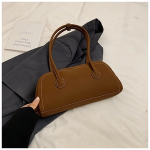 Detail of brown retro tote bag with white contrast stitching and matte leather texture