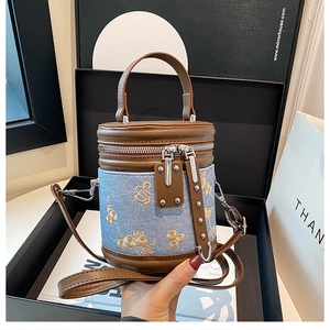 Détail du sac seau en jean avec broderie florale dorée dans son emballage cadeau chic