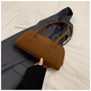 Close-up of caramel brown leather tote with contrast white stitching on a gray blazer