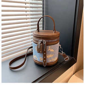Détail de broderie florale sur sac seau en denim avec finitions cuir brun et rivets argent