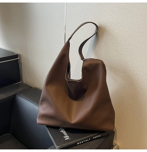 Detail of soft brown pebble leather tote bag with elegant slouchy texture on a book