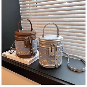 Détail de la broderie florale sur sacs seau en denim avec finitions cuir et argentées