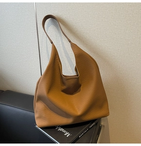 Detail of caramel brown pebbled leather texture on a large minimalist tote bag