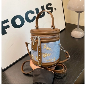 Détail de la broderie florale sur le sac seau en cuir marron et denim avec double zip