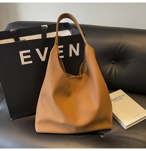 Detail of caramel brown leather hobo bag with pebble texture on a black sofa background