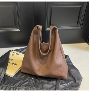 Detail of brown lychee texture leather hobo bag on a stylish black leather background