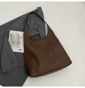 Detail of dark brown leather tote bag with lychee texture on grey blazer
