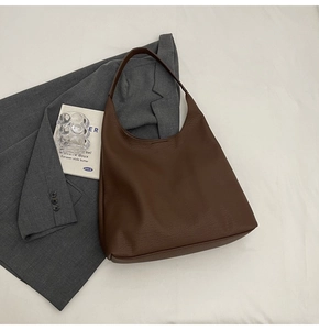 Detailed view of dark brown pebbled leather tote bag styled with a grey blazer