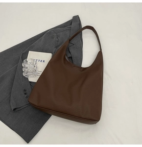 Macro shot of dark brown pebbled leather texture on a minimalist large hobo tote bag