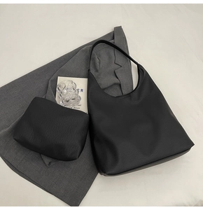 Detail view of black textured leather tote bag set with matching small pouch and silver hardware