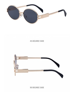 Detail of oval metal sunglasses with golden geometric engravings and dark gray lenses