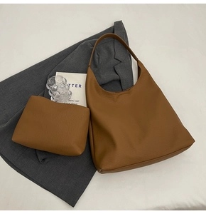 Detail of caramel brown textured tote bag with matching zipper pouch and chic accessories