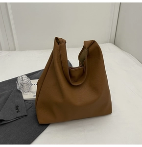 Detail shot of brown lychee grain faux leather tote bag on casual workplace backdrop