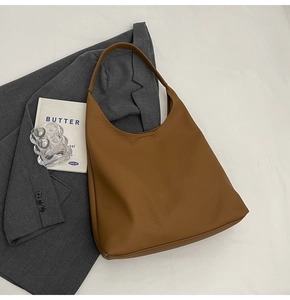 Detail shot of large caramel leather tote bag with wide strap on minimalist background