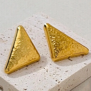 Détails macro de boucles d'oreilles en acier inoxydable doré à texture martelée
