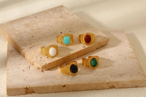 Macro shot of five vintage gold-toned rings with colorful natural stones on stone props