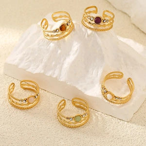 5-piece gold plated adjustable rings set with oval gemstones on minimalist white stone stand