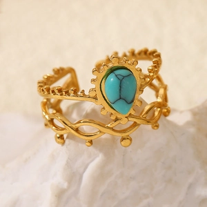 Macro detail of gold-plated ring featuring turquoise stone on white rock texture