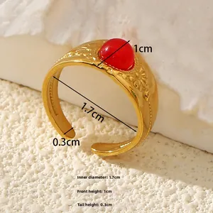 Close-up of vintage gold ring with red gemstone and embossed floral pattern details